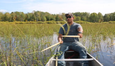 Darin Powell beats rice kernel into the hull of his canoe.